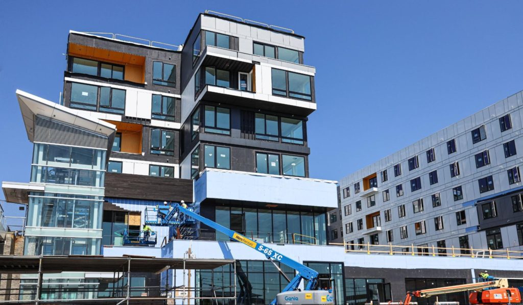 A multi-story commercial building under construction, featuring a large number of black-framed glass windows, walls and doors from Paradigm.